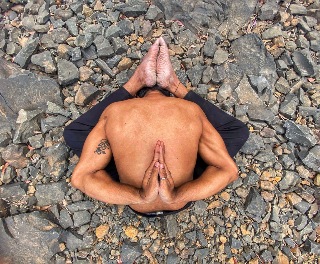 why-choose-us A man performs a complex yoga pose on rocky ground, showcasing strength and flexibility.