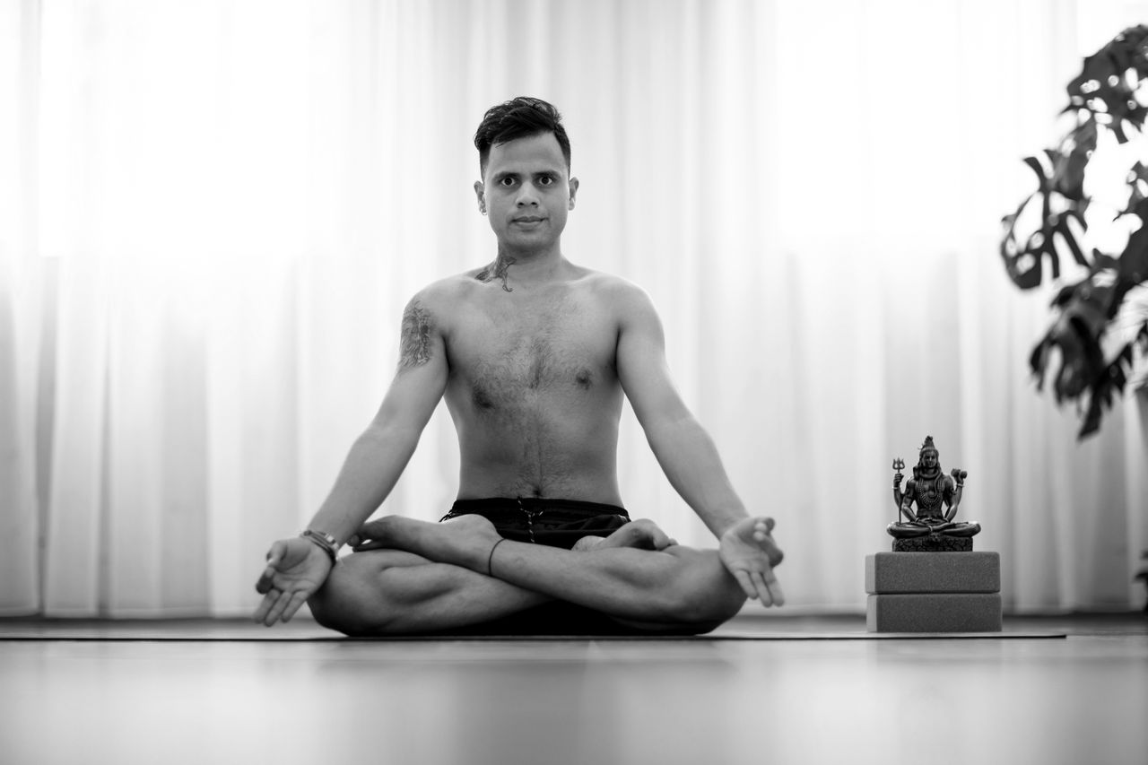 services-01 A man practicing yoga in a peaceful indoor setting, in black and white.