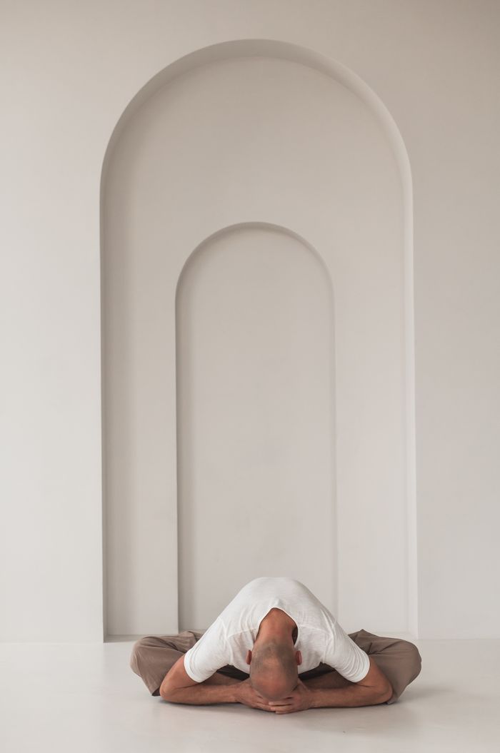 team-01 Man practicing meditation in a minimalist space with white arches, embodying serenity and focus.