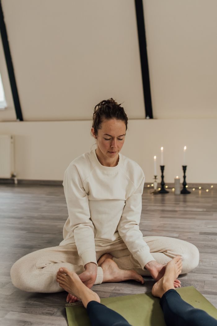 team-03 A serene indoor meditation therapy session with a woman in comfortable attire facilitating a calming environment.