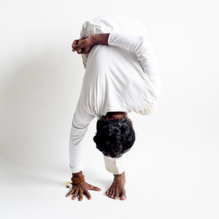 services-04 A man performs an advanced yoga pose showcasing flexibility and balance on a white background.